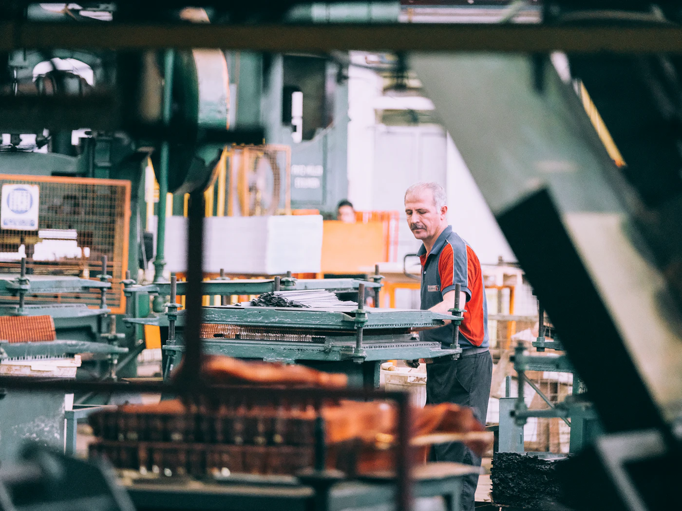 An operator working at industrial machinery on a workshop floor