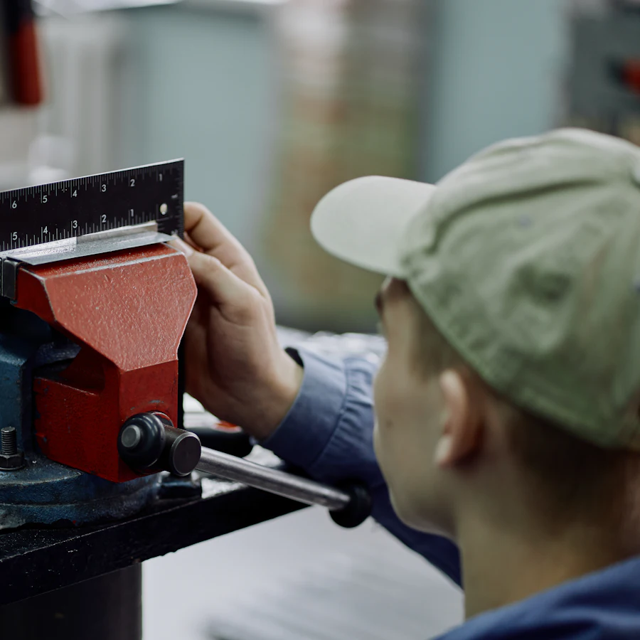 A worker checking the dimensions of a metal component in a vise