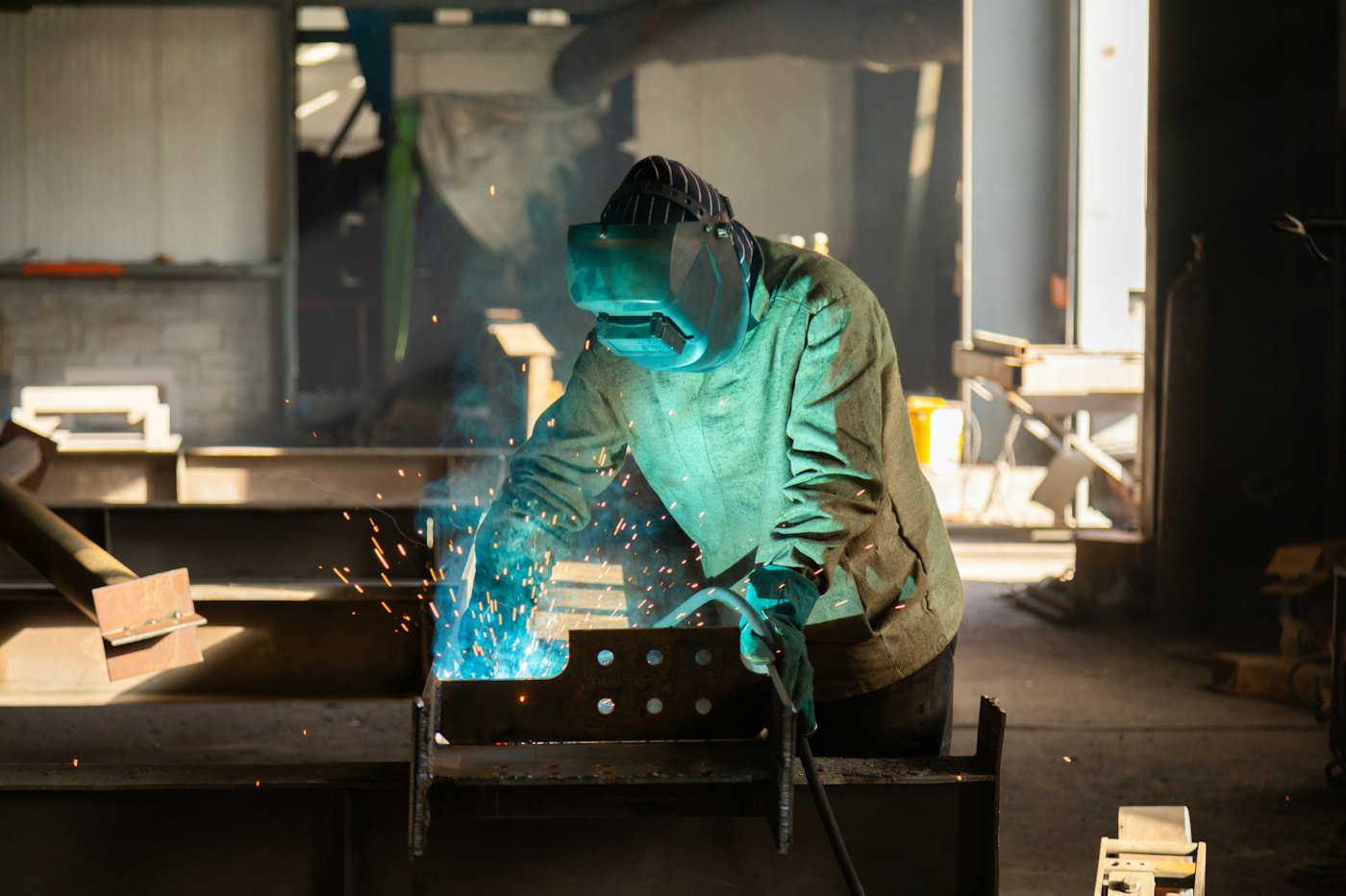 A welder using a torch on a metal frame while wearing a protective helmet